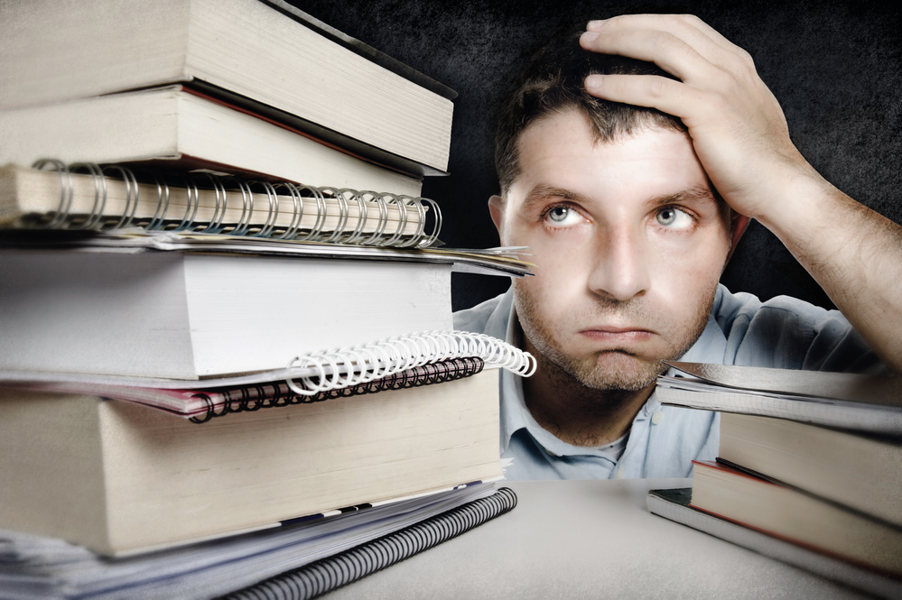 man with books looking frustrated